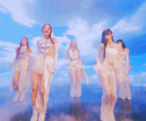 a group of women are dancing in front of a cloudy sky