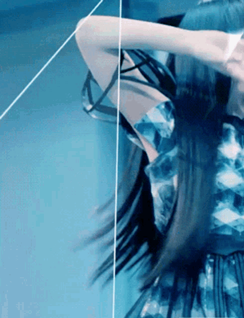 a woman in a blue dress is standing in front of a mirror and her hair is blowing in the wind