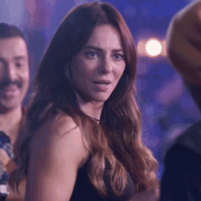 a woman in a black tank top is looking at the camera
