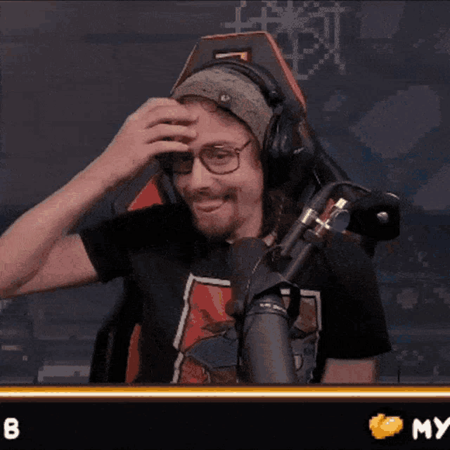 a man wearing headphones and glasses is sitting in front of a microphone with the number 8 in the corner