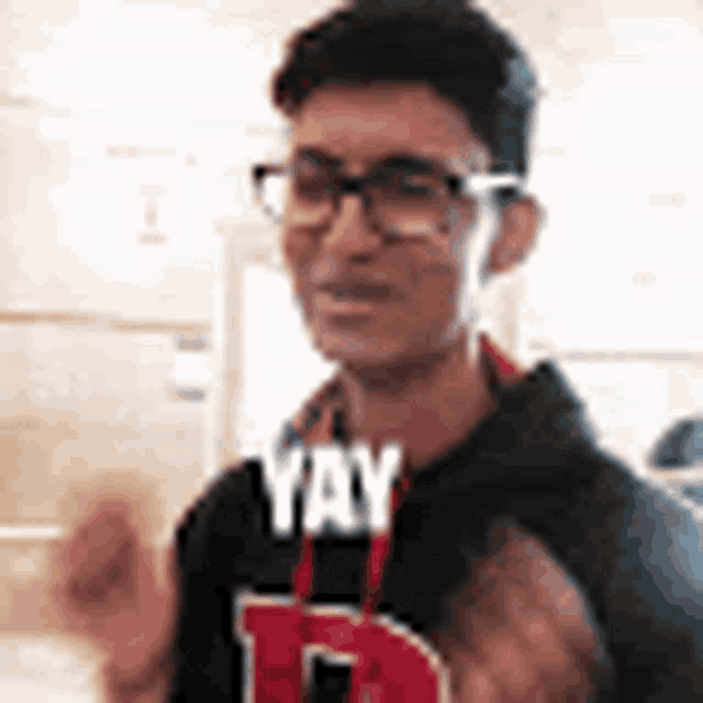 a young man wearing glasses and a sweatshirt with the word yay on it .