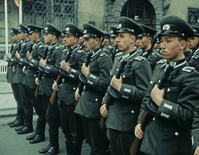 a group of men in military uniforms are standing in a line holding guns