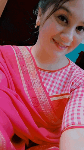 a woman wearing a pink blouse and a pink saree smiles at the camera