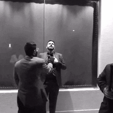 a man in a suit is standing in front of a mirror