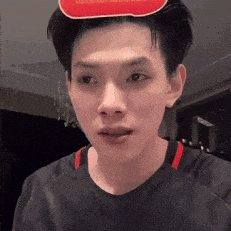 a young man wearing a black shirt and a red and white hat .