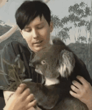 a woman is holding a koala bear in her arms while petting it .