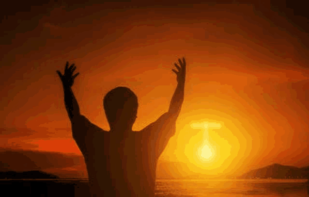 a man is standing with his arms outstretched in front of a cross .