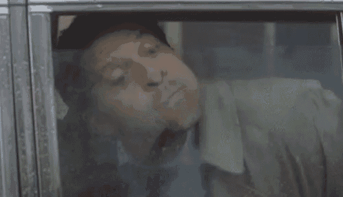 a man is laying in a car with his mouth open and his tongue sticking out .