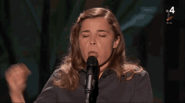 a woman singing into a microphone with the number 4 on the bottom