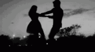 a black and white photo of a man and a woman holding hands .