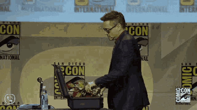 a man in a suit is standing in front of a sign that says comic con