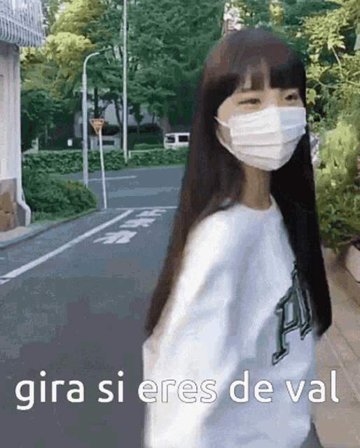 a girl wearing a face mask is walking down a street with the words gira si eres de val below her