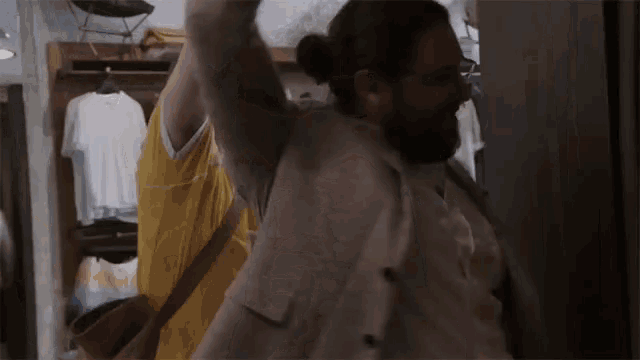 a man with a beard is dancing in a closet