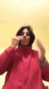 a woman in a red jacket is blowing a kiss with her hands .