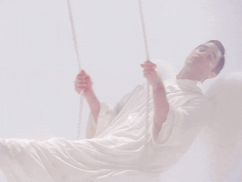 a man in a white angel costume is swinging on a rope
