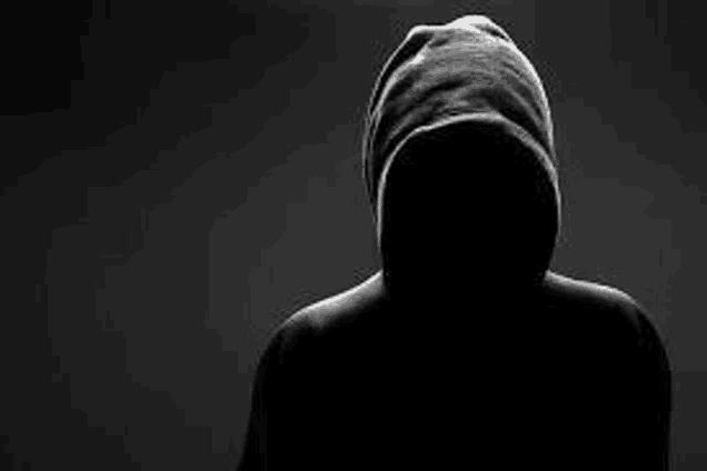 a silhouette of a man in a hoodie with his face covered in the dark .