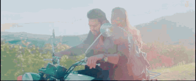 a man and a woman are riding a motorcycle in the countryside .