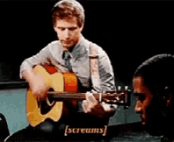 a man is playing an acoustic guitar while another man screams in the background