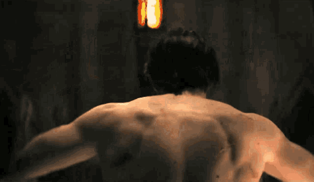 a man without a shirt is standing in front of a fire