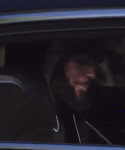 a man is sitting in the back seat of a car looking out the window .
