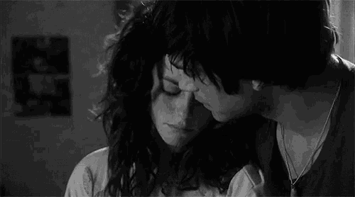a black and white photo of a man and a woman hugging and kissing .