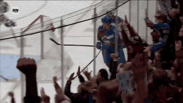 a hockey player stands in front of a crowd with a sign that says we 're here