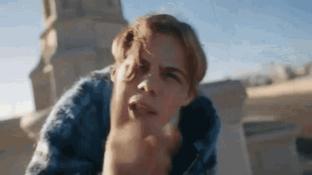 a young man is making a funny face while standing on a rooftop .