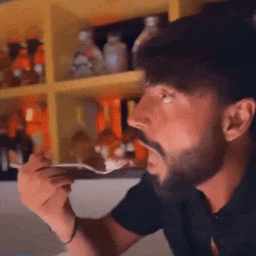 a man with a beard is eating food from a spoon .