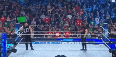 two wrestlers are standing in a wrestling ring with a sign that says ko on it .