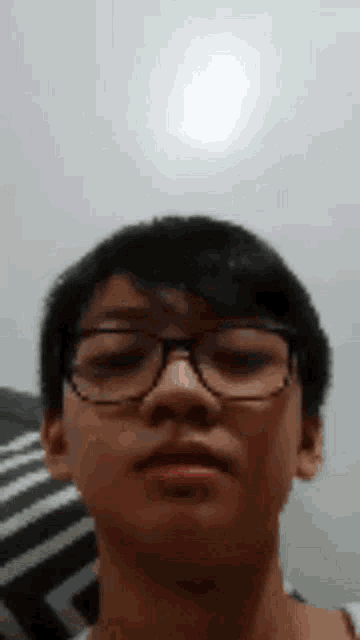 a young man wearing glasses is making a funny face and looking at the camera .