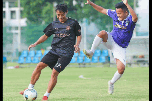 a soccer player wearing a black jersey with the word etihad on it kicks the ball