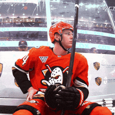 a hockey player holding a stick in front of a sign that says troutman armour