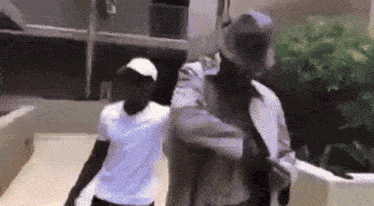 a man in a white shirt is standing next to a man in a hat .