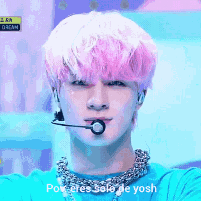 a young man with pink hair is wearing a microphone and a necklace