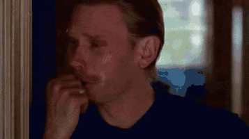 a man is talking on a cell phone while standing next to a wall .