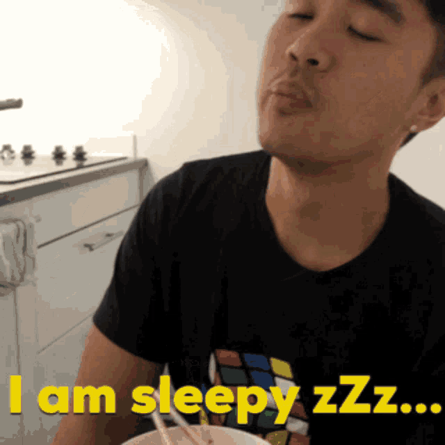 a man wearing a black shirt with a rubik 's cube on it says i am sleepy zzz