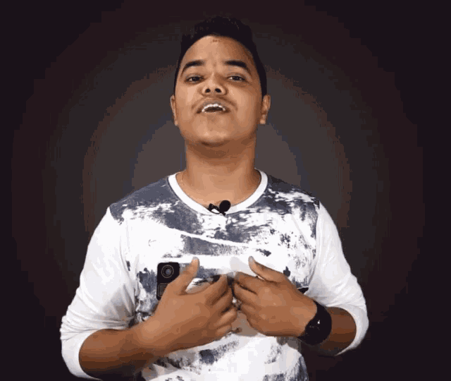 a young man wearing a blue and white shirt has a small camera on his chest