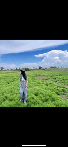 a woman wearing a hat is standing in a field of grass