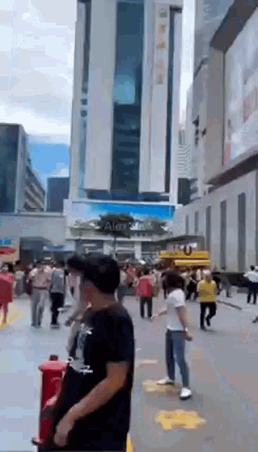 a crowd of people are walking down a street in front of a building that says alex on it