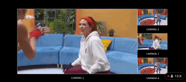 a woman is sitting on a blue couch in front of a screen that says camara 1