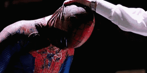 a man in a spiderman costume is being punched in the face .