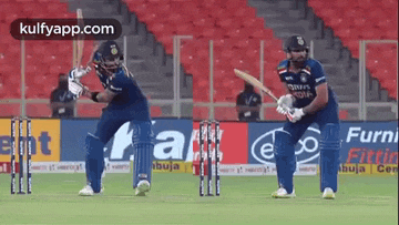 two cricket players are playing a game of cricket in front of a crowd .