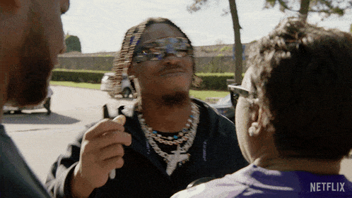 a man wearing sunglasses talks to another man with a netflix logo on his shirt