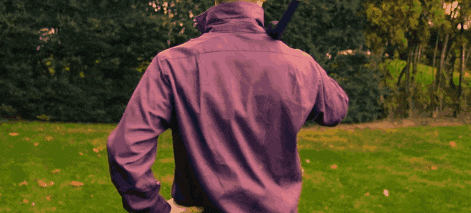 a man in a purple shirt stands in a grassy field