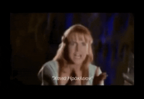 a woman in a blue shirt is making a funny face while talking in a foreign language .