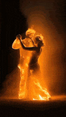 a man and a woman are dancing in a fire filled room .