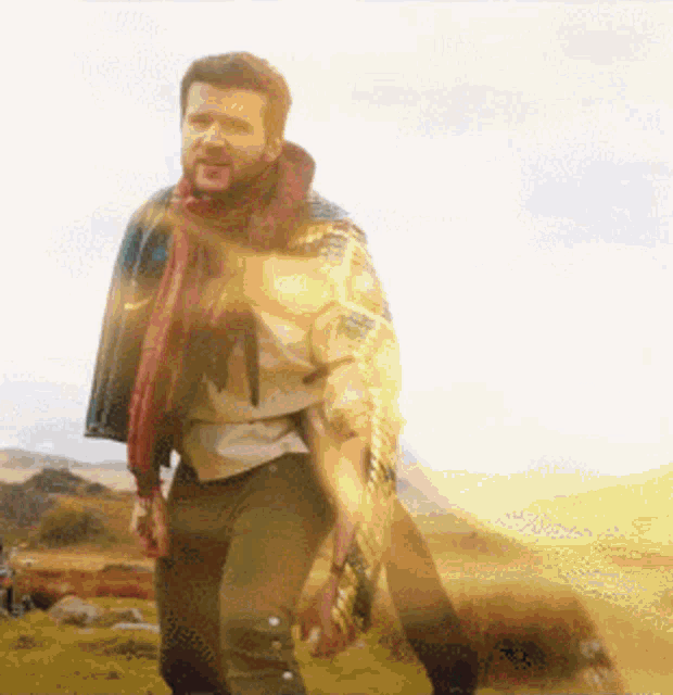 a man with a scarf around his neck is walking through a field