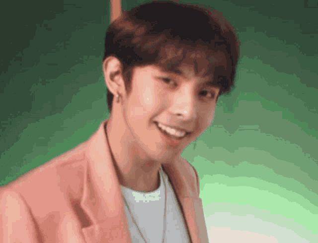 a young man is wearing a pink jacket and smiling .
