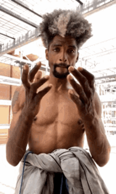 a shirtless man with a beard is holding something in his mouth with his hands