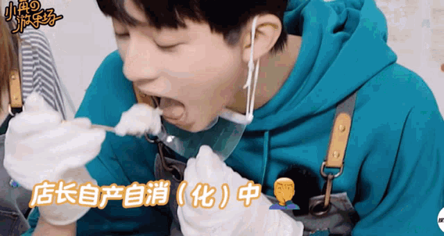 a man in a blue hoodie is eating something with chinese writing on the bottom